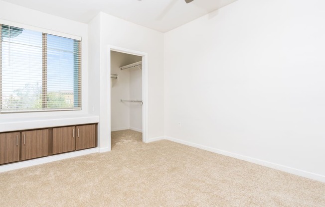 an empty room with a large window and a closet