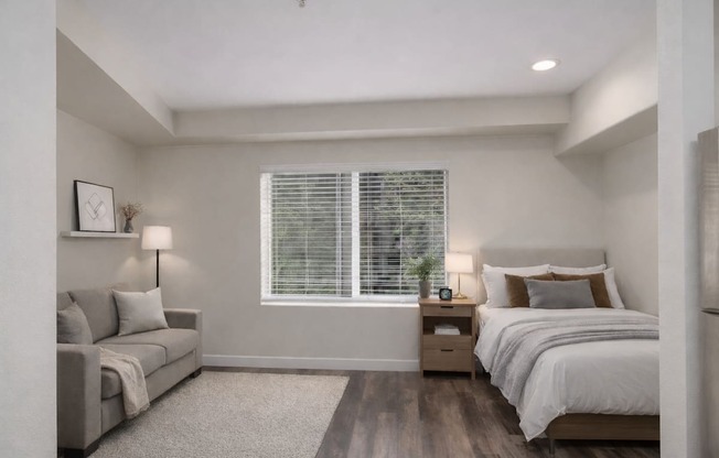 A bedroom with a bed, nightstand, and couch.