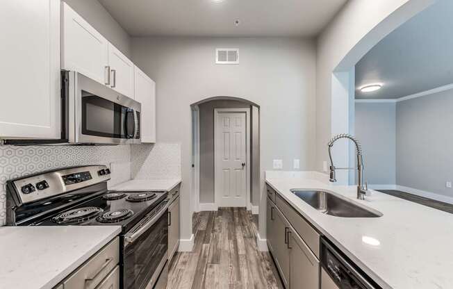 A kitchen with a stove, microwave, and sink.