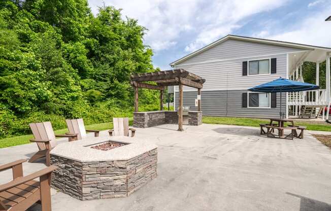 a patio with a fire pit and a house in the background