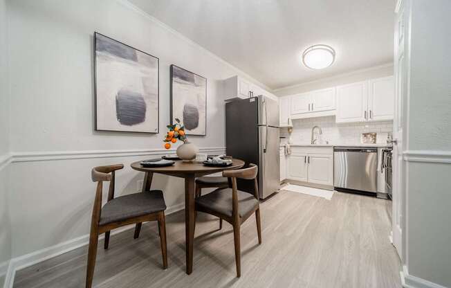 A kitchen with a table and chairs in the foreground and a refrigerator in the background.