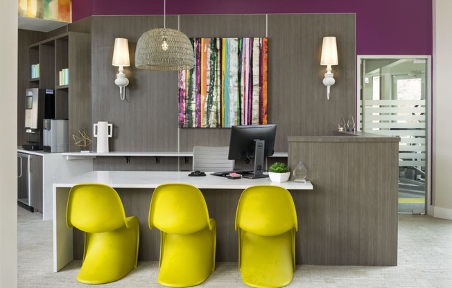 an office with purple walls and a desk with three yellow chairs