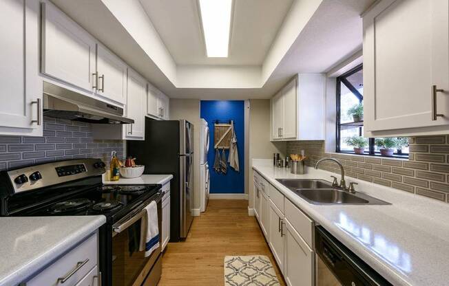 A kitchen with white cabinets and a black refrigerator.