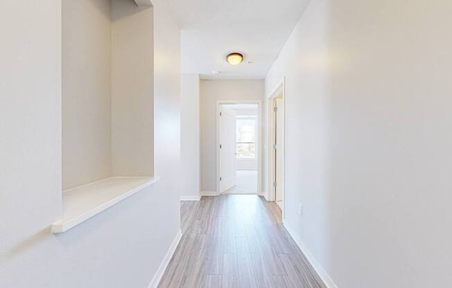 A long white hallway with a door at the end.