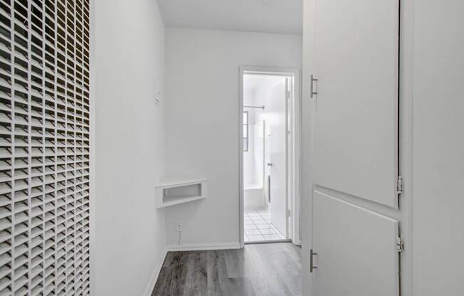 a small hallway with a white wall and a door to a white room