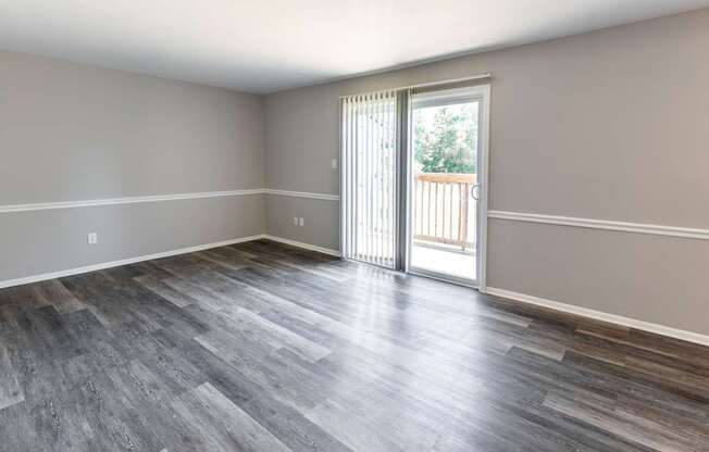 an empty living room with a sliding glass door to a balcony