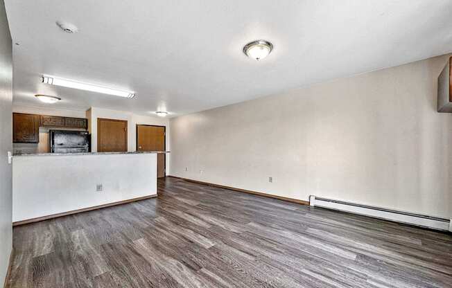 an empty living room with a white wall and wood flooring