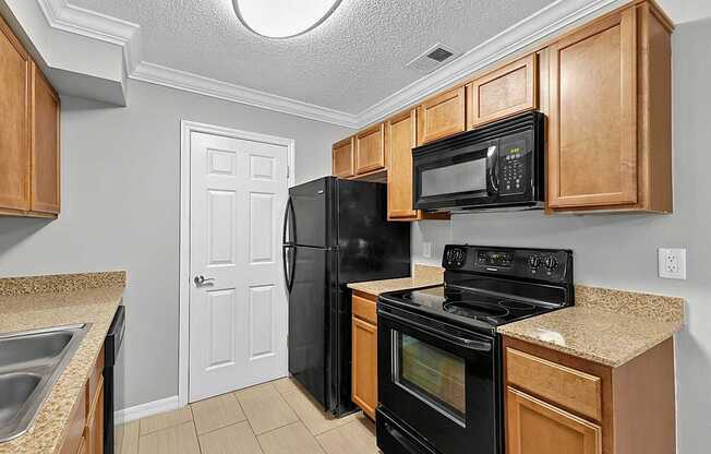 A kitchen with black appliances and wooden cabinets.