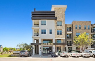 A modern building with a leasing center sign in front.