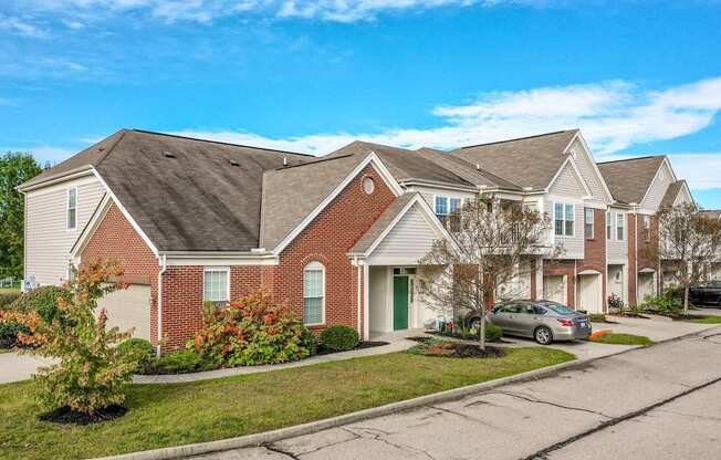 A row of houses with a car parked in front of the first one.