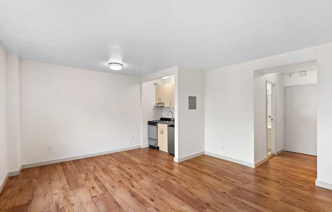 a living room and kitchen with wood floors and white walls