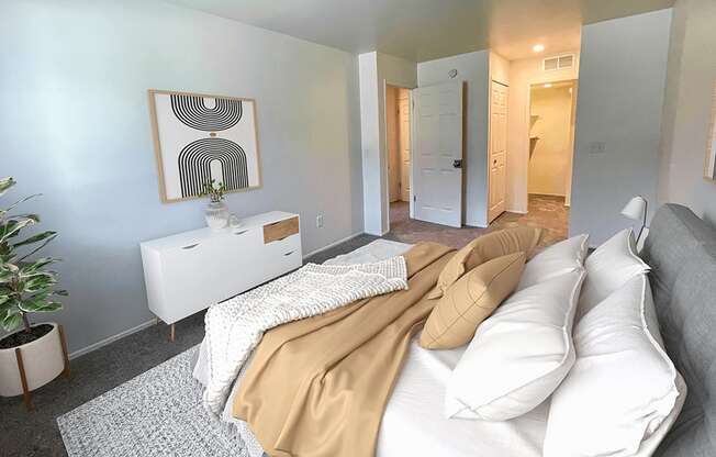 a bedroom with a bed with white pillows and a tan blanket