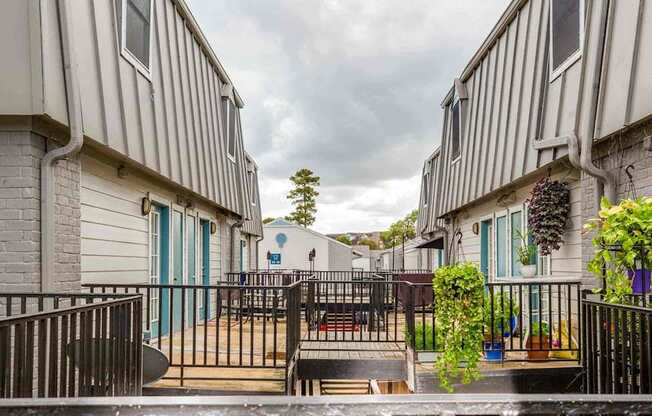 A view of a courtyard between two buildings with a metal fence and a small tree in the middle.