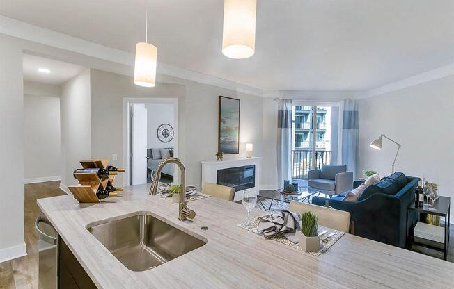 a kitchen with a sink and a counter in front of a living room at Aster Apartments, Ohio, 44122