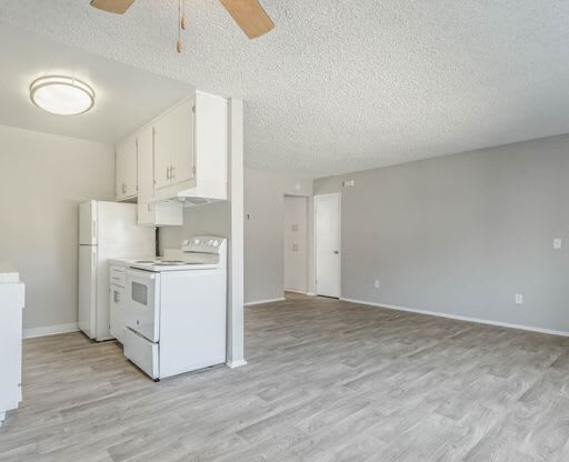 an empty living room with a kitchen and a ceiling fan at The Arches Apartments, El Cajon, CA 92021