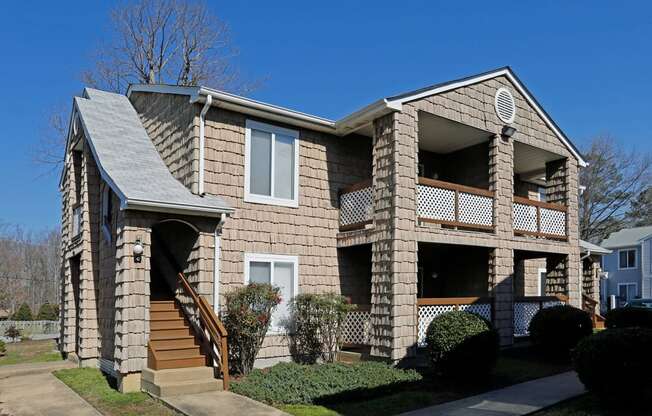 a tan brick house with a porch and stairs