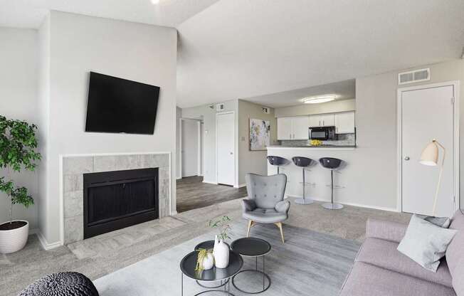 A living room in the A3 floorplan with white walls, a stone fireplace, and a grey couch at Jefferson Creek Apartments in Irving, TX