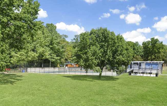 A green field with trees and a building in the background.
