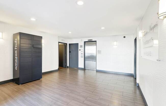 A hallway with a wooden floor and a white wall with a door on the right side.