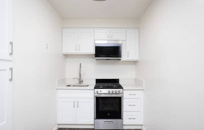 A white kitchen with a stove and microwave.