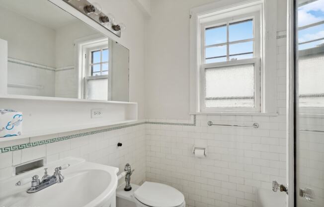 a white bathroom with a sink toilet and a window