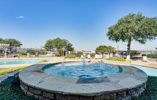 a fountain in a park with a pool and trees