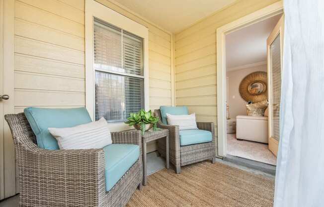 a porch with two wicker chairs and a table at Highland Ridge Apartments, Overland Park , Kansas