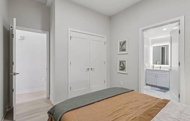 A bedroom with a bed, two doors, and a mirror.