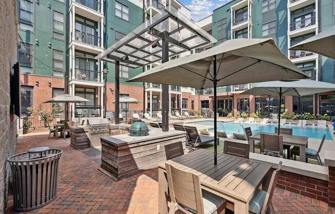 A pool area with a table and chairs and umbrellas.