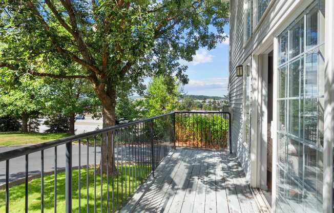 the view from the deck of a home with a large tree and a balcony