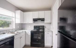 A kitchen with black appliances and white cabinets.