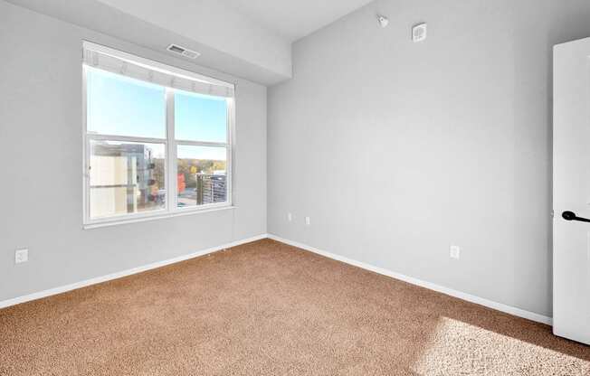 A room with a carpeted floor and a large window.
