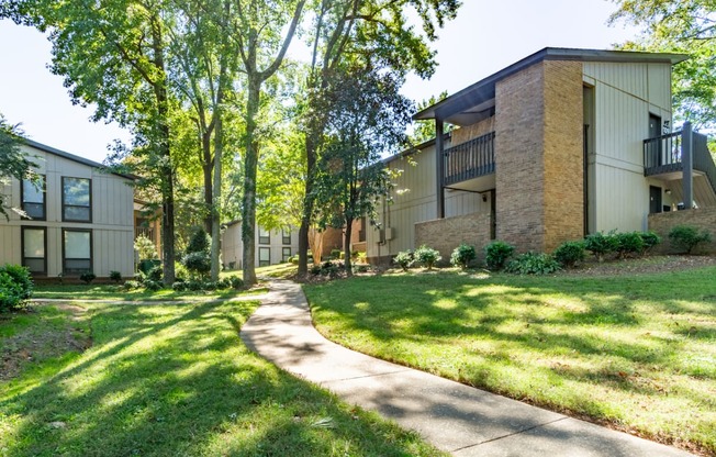 a sidewalk in front of a building with grass and trees