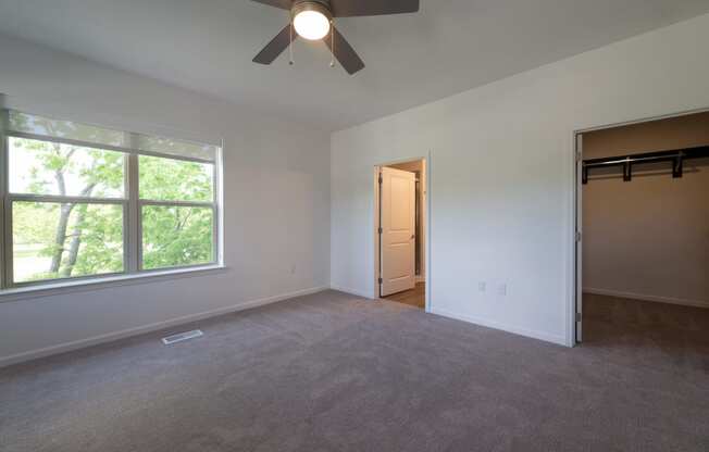 an empty living room with a large window and a ceiling fan at The Clearing at ONE28, Olathe