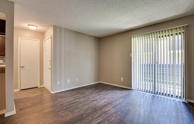 an empty living room with a large window and wood flooring