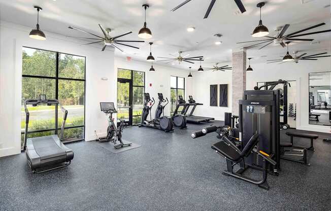 a gym with weights and cardio equipment and windows
