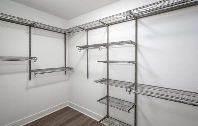 a spacious walk in closet with empty shelves and white walls