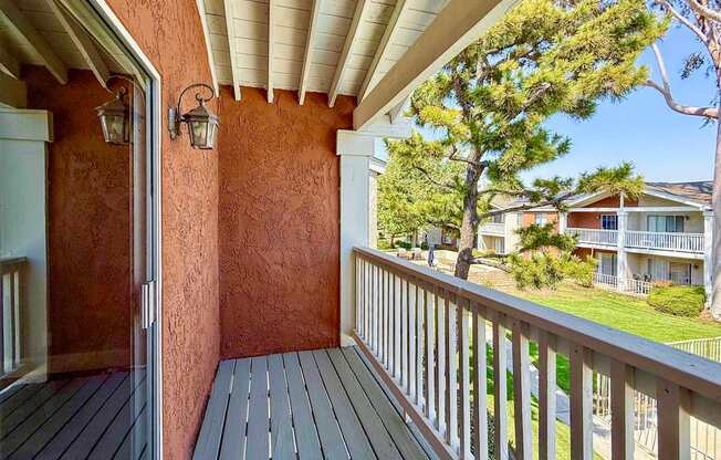 A balcony with a wooden floor and a white railing.