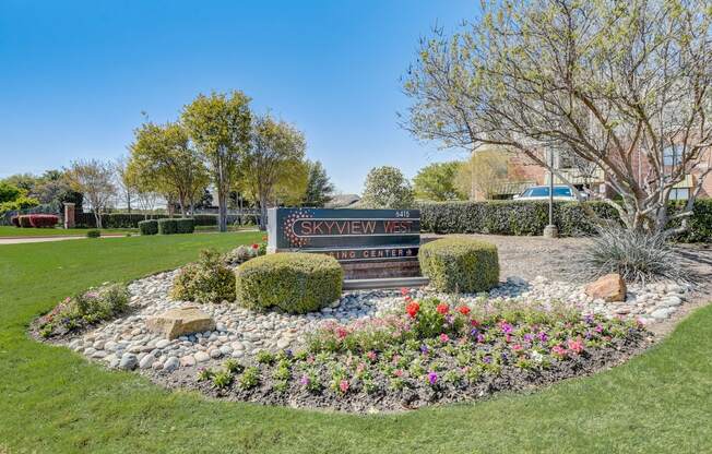 a park with flowers and a sign in the grass