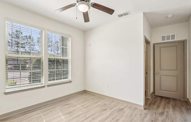A room with a ceiling fan and a door leading to another room.