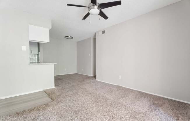 A room with a ceiling fan and carpeted floor.