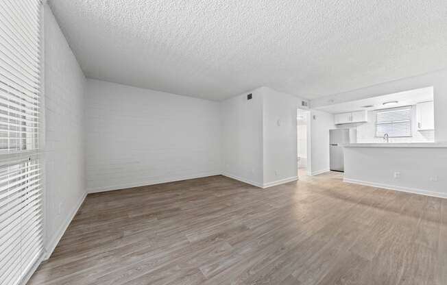 a bedroom with hardwood floors and a kitchen in the background