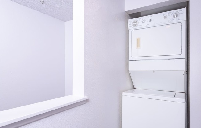 a white washer and dryer in a room with white walls and a window