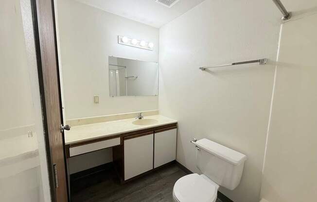 A white toilet sits in a bathroom next to a sink and mirror.