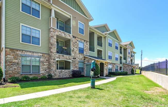 a row of apartment buildings with green grass and a sidewalk