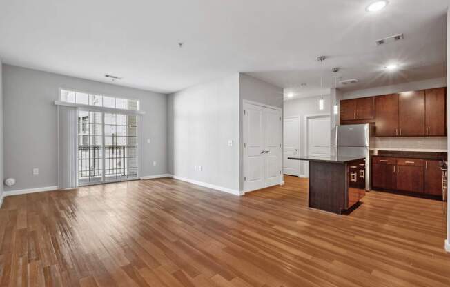 A spacious kitchen with wooden floors and white walls.