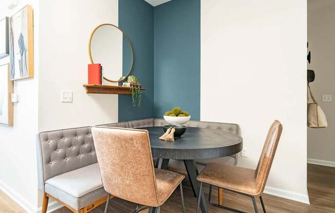 A grey chair with a tufted back sits in front of a round table.
