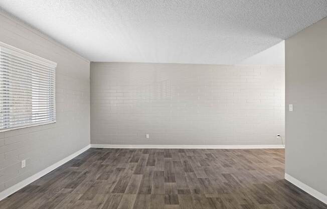 A room with wooden flooring and a window with blinds.