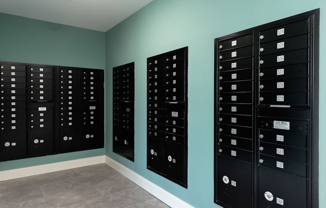 Three black mailboxes on a wall.