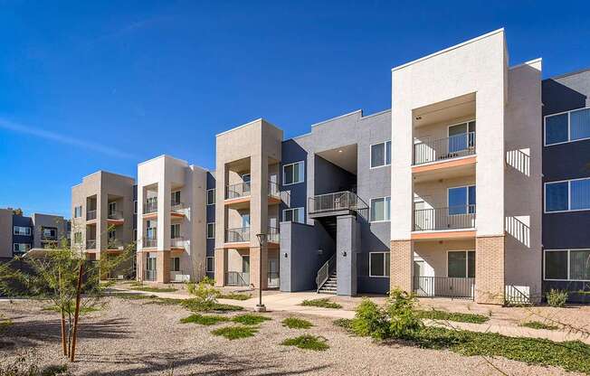 A modern apartment complex with multiple balconies and a clear blue sky.